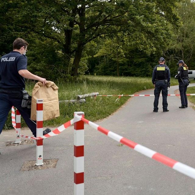 Einsatzkräfte der Polizei stehen hinter einer Absperrung an einem Weg in Neukölln, wo ein Polizist am frühen Morgen einen toten Säugling gefunden hat.
