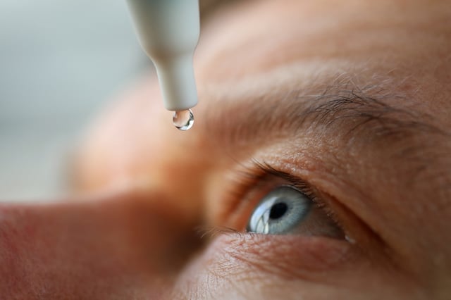Stock image of a man applying eye drops.