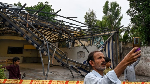 A man takes a picture in front of the wreckage of a restaurant's shade outside the Rawalpindi cricket stadium after an alleged drone was shot down in Rawalpindi on May 8.
