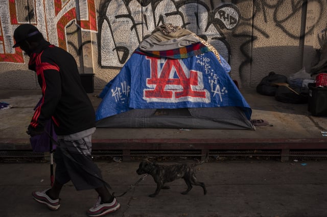 FILE - A man walks past a homeless encampment in downtown Los Angeles, Oct. 25, 2023. (AP Photo/Jae C. Hong, File)