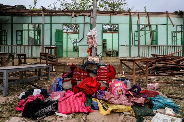 Over a dozen abandoned book bags were piled before a pole flying the Myanmar flag outside the school building