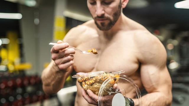 Powerful athletic man with great physique eating a healthy salad. Mockup your brand