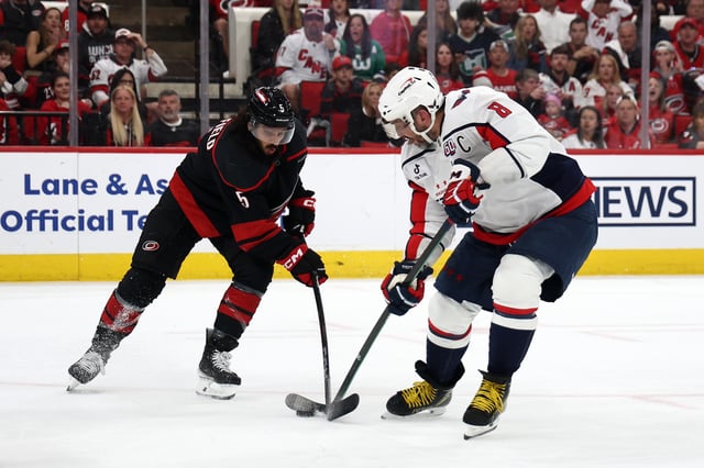 Alex Ovechkin #8 of the Washington Capitals skates with the puck while defended by Jalen Chatfield #5 of the Carolina Hurricanes during the first period in Game Three of the Second Round of the 2025 Stanley Cup Playoffs at Lenovo Center at Lenovo Center on May 10, 2025 in Raleigh, North Carolina.