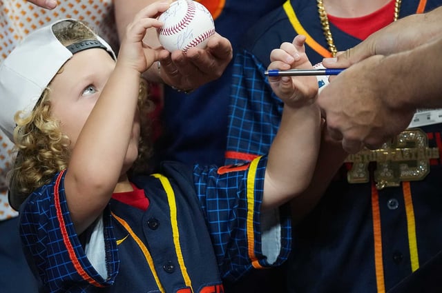 A young Houston Astros fan gets Houston Astros outfielder Cam Smith (11) autograph after batting practice before they take on Kansas City Royals at Daikin Park in Houston on Monday, May 12, 2025.