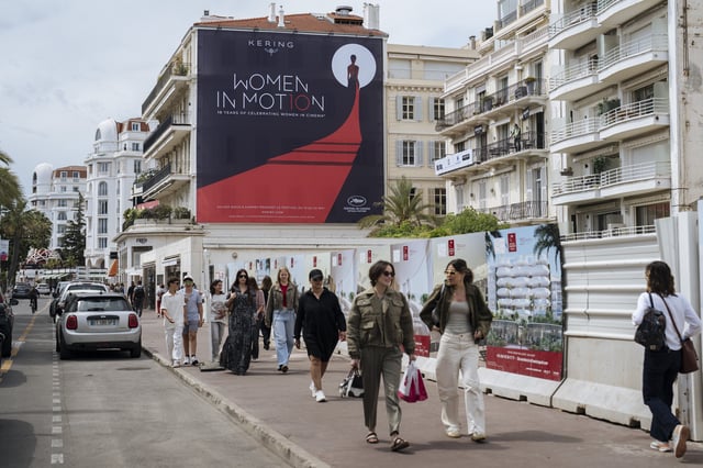 People walk along the Boulevard de la Croisette ahead of the 78th international film festival in Cannes, southern France, Sunday, May 11, 2025. The Cannes film festival runs from May 13 until May 24, 2025. (AP Photo/Lewis Joly)