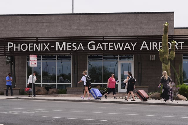 Passengers walk in front of Mesa Gateway Airport, where Avelo Airlines started making deportation flights on behalf of the federal government on Monday, May 12, 2025, in Mesa, Ariz. (AP Photo/Ross D. Franklin)