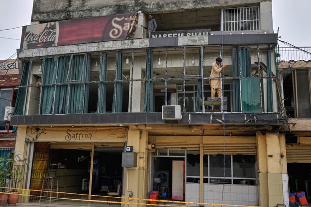 Workers repair broken glass of a building at the parking area of Rawalpindi Cricket Stadium, where a suspected Indian drone was crashed on Thursday, in Rawalpindi, Pakistan, Friday, May 9, 2025. (AP Photo/Anjum Naveed)
