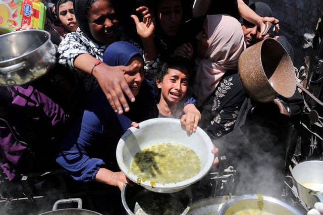 A Palestinian receives food cooked by a charity kitchen, in Beit Lahia, northern Gaza Strip, May 8, 2025. REUTERS/Mahmoud Issa/File Photo NO RESALES. NO ARCHIVES.