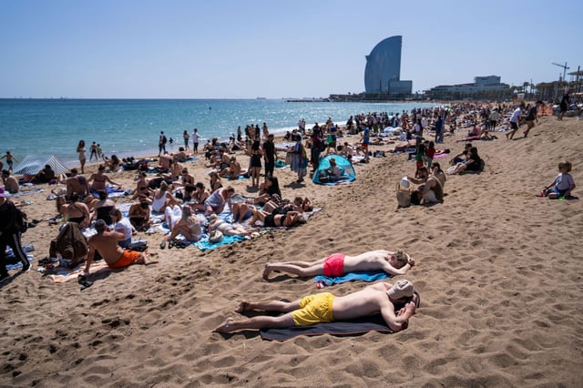 Cientos de turistas disfrutando del sol y la playa de la Barceloneta.