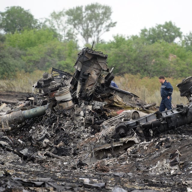 (FILES) Rescuers stand on July 18, 2014 on the site of the crash of a Malaysian airliner carrying 298 people from Amsterdam to Kuala Lumpur, near the town of Shaktarsk, in rebel-held east Ukraine. The United Nations aviation agency said on May 12, 2025 that Russia was responsible for the downing of a Malaysian Airways jetliner over Ukraine in 2014, with the death of 298 people. The International Civil Aviation Organization, based in Montreal, said claims brought by Australia and the Netherlands over the shooting down of Flight MH17 on July 17, 2014 were "well founded in fact and in law." (Photo by DOMINIQUE FAGET / AFP) (Photo by DOMINIQUE FAGET/AFP via Getty Images)