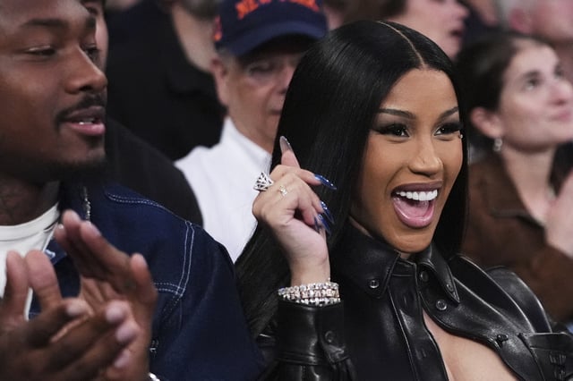 Stefon Diggs, left, claps as Cardi B poses for fans during NBA basketball playoffs between New York Knicks and Boston Celtics Monday, May 12, 2025, in New York.