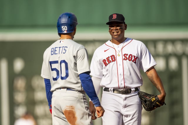 BOSTON, MA - AUGUST 26: Mookie Betts #50 of the Los Angeles Dodgers reacts with Rafael Devers #11 of the Boston Red Sox during the first inning of a game on August 26, 2023 at Fenway Park in Boston, Massachusetts.