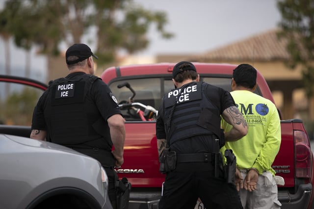 A U.S. Immigration and Customs Enforcement (ICE) officers detain a man during an operation in Escondido, Calif.
