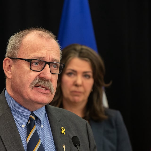 Minister of Municipal Affairs Ric McIver speaks as Alberta Premier Danielle Smith looks on during a press conference in Edmonton, Wednesday, April 10, 2024. McIver has resigned from cabinet amid speculation he will run for the vacant position of Speaker of the house. THE CANADIAN PRESS/Jason Franson