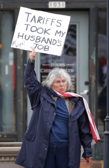 A woman's sign claims tariffs took her husbands job during the anti-Trump protest on May 1, 2025, in Sheboygan, Wisconsin.