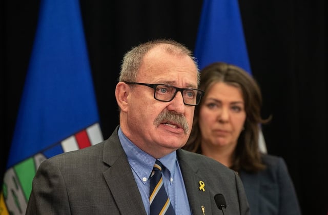 Minister of Municipal Affairs Ric McIver speaks as Alberta Premier Danielle Smith looks on during a press conference in Edmonton, Wednesday, April 10, 2024. McIver has resigned from cabinet amid speculation he will run for the vacant position of Speaker of the house. 