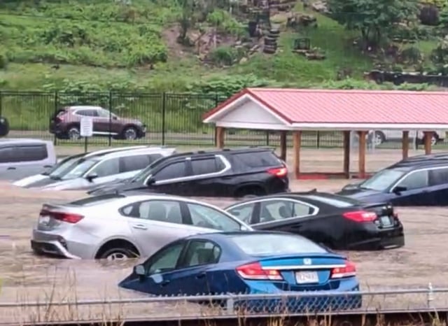 Cars are submerged in a parking lot of Westernport Elementary School as flooding forces the evacuation of the school, and downtown homes and businesses were inundated with rising floodwaters in rural Westernport, Md., Tuesday, May 13, 2025. (Aaron Stallings via AP)