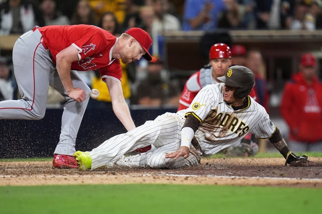 The San Diego Padres’ Manny Machado, right, scores on a wild pitch as Angels relief pitcher Ryan Zeferjahn drops the ball while covering home plate during the eighth inning on Tuesday night in San Diego. The Angels lost, 6-4. (AP Photo/Gregory Bull)