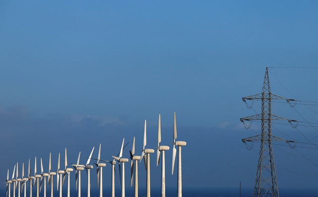 High-voltage power lines and an electricity pylon next to a group of wind turbines are pictured in Barranco de Tirajana, in the island of Gran Canaria, Spain, May 11, 2022. REUTERS/Borja Suarez/File Photo