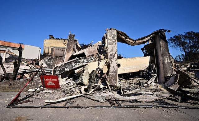 A State Farm insurance company sign sits amid the rubble of a building destroyed by the Palisades Fire on Sunset Boulevard in the Pacific Palisades neighborhood of Los Angeles on January 16, 2025.
