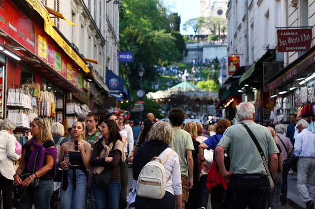 Tourists walk along a street at the Butte Montmartre on a warm and sunny Spring day in Paris, France, April 29, 2025. REUTERS/Abdul Saboor/File Photo