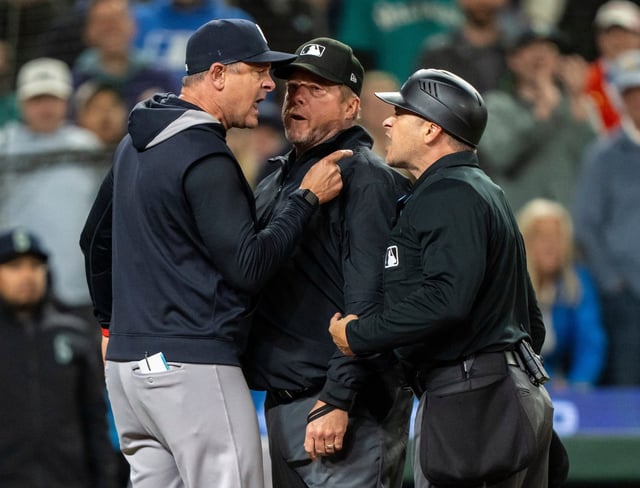 New York Yankees manager Aaron Boone, left, argues with home plate umpires Mark Wegner, right, and first base umpire Bruce Dreckman after getting thrown out of a baseball game against the Seattle Mariners in the ninth inning, Tuesday, May 13, 2025, in Seattle. (AP Photo/Stephen Brashear)
