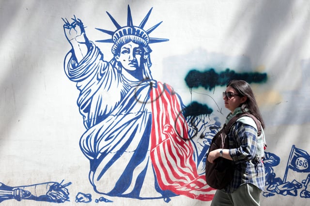 TOPSHOT - A woman walks next to an anti-US mural near the former US embassy in Tehran May 11, 2025.