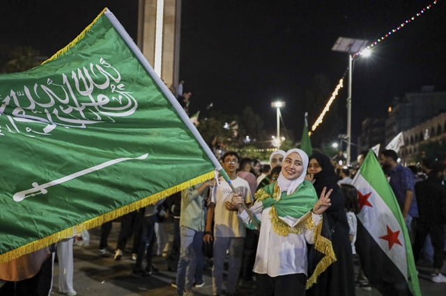 A girl holds a Saudi flag in Homs, Syria, Tuesday, May 13, 2025, as she celebrates U.S. President Donald Trump's plan to ease sanctions on Syria and normalize relations with its new government. Trump made the announcement on a visit to Saudi Arabia. (AP Photo/Omar Albam)