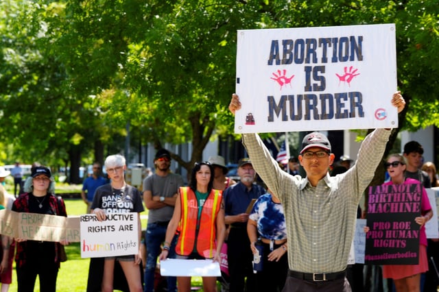 FILE - A man supporting restrictions on abortion holds a sign as abortion-rights supporters hold signs behind him outside the South Carolina Statehouse on Thursday, July 7, 2022, in Columbia, S.C. (AP Photo/Meg Kinnard, file)