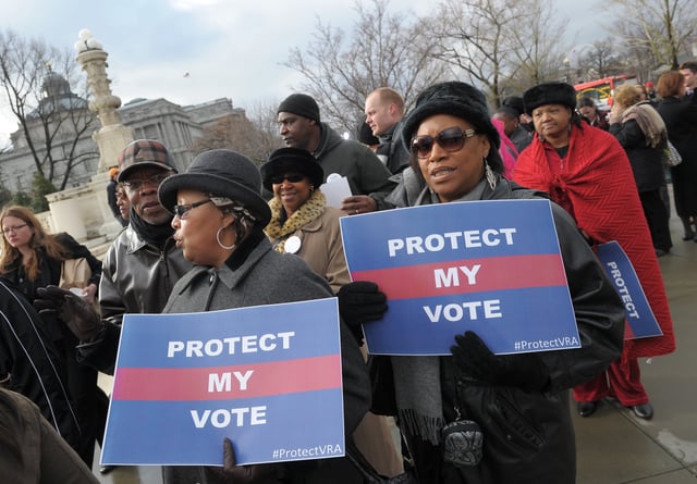 Activists hold a pro-voting rights placards outside of the US Supreme Court on February 27, 2013 in Washington, DC as the Court prepares to hear Shelby County vs Holder.