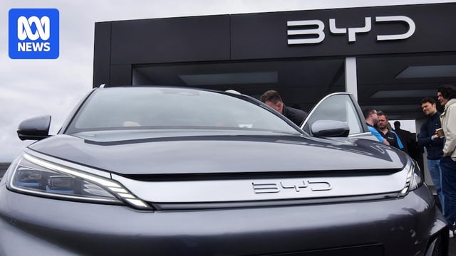 People looking inside the interior of a medium-sized vehicle at a car dealership.