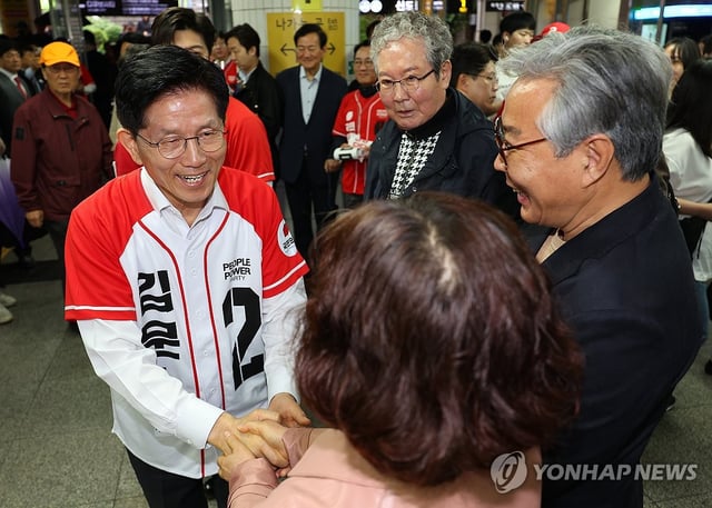 Kim Moon-soo (R), the presidential candidate of the conservative People Power Party, shakes hands with a supporter during a campaign stop in a subway station in Seoul on May 15, 2025, ahead of the June 3 presidential election. (Pool photo) (Yonhap)