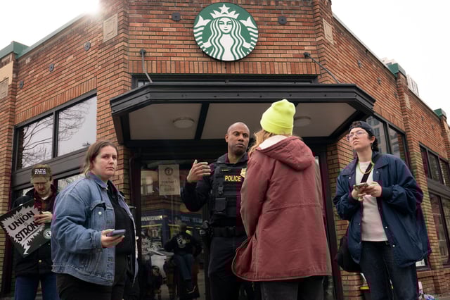 Starbucks workers and their supporters negotiate with a police officer outside of a Starbucks retail location during a strike and rally organized by Starbucks Workers United in Seattle on March 11, 2025.