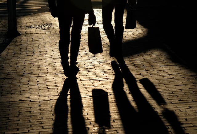 Shoppers cast shadows as they carry their bags along the waterfront in Portland, Maine, U.S, December 26, 2024.  REUTERS/Kevin Lamarque/File photo