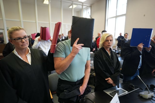 Die elf Angeklagten stehen zu Beginn des Prozesses wegen Drogenhandels im Sitzungssaal.