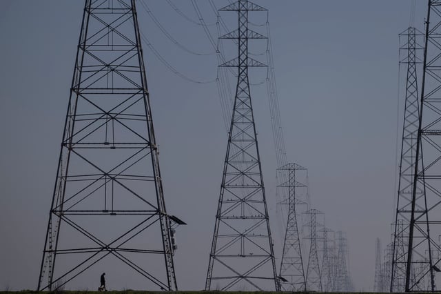 A local resident walks by the power grid towers at Bair Island State Marine Park in Redwood City, California, United States, January 26, 2022. REUTERS/Carlos Barria/ File Photo