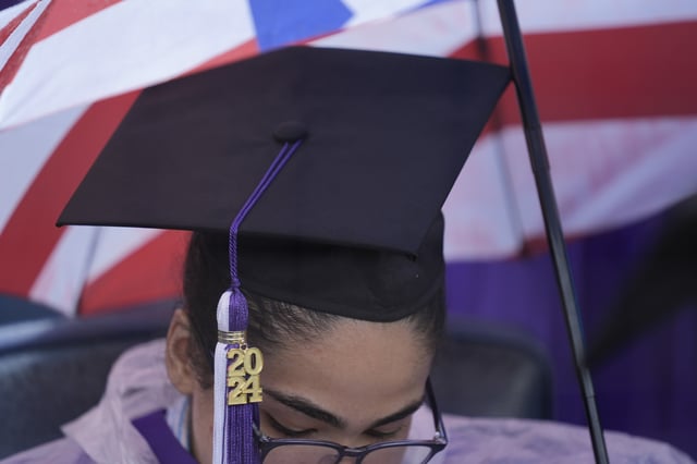 FILE - A New York University graduate sits in the rain before the start of the commencement ceremony at Yankee Stadium in New York, May 15, 2024. (AP Photo/Seth Wenig, file)