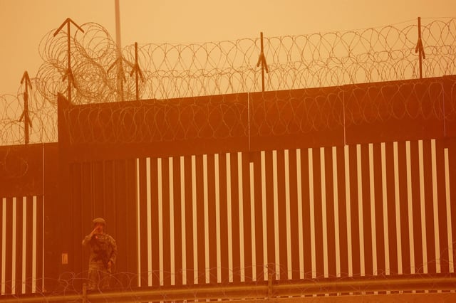 A Texas National Guard soldier stands near the wall on the border between Mexico and U.S. during a sandstorm, as seen from Ciudad Juarez, Mexico March 6, 2025. REUTERS/Jose Luis Gonzalez/File Photo