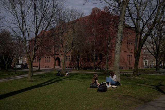 People sit on the grass at the campus of Harvard University in Cambridge, Massachusetts, U.S., April 15, 2025.   REUTERS/Faith Ninivaggi/File Photo