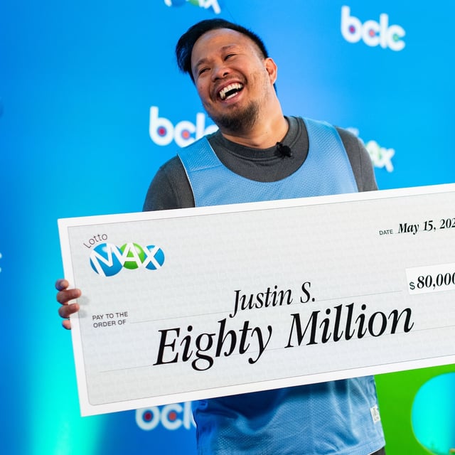 Justin Simporios from Surrey holds a cheque during an announcement for the British Columbia Lottery Corporation's $80 million lottery winner in Vancouver on Thursday, May 15, 2025. THE CANADIAN PRESS/Ethan Cairns