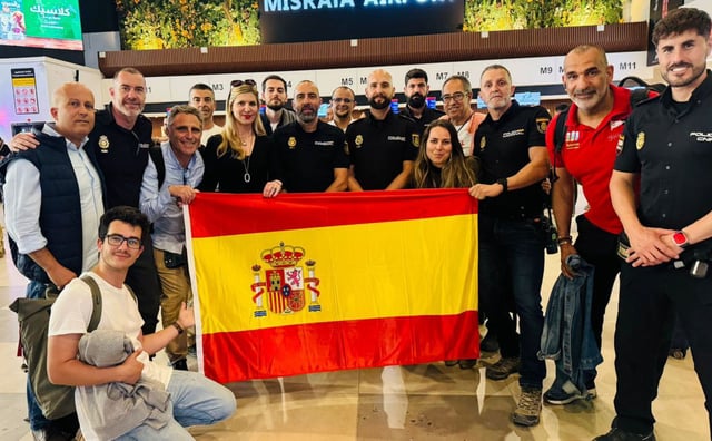 Begoña Fernández, sosteniendo la bandera española, con los otros miembros del grupo y agentes en Libia, antes de partir.