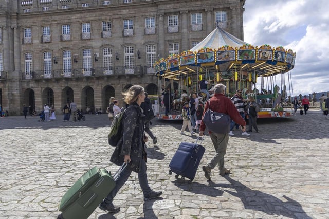 Dos turistas con sus maletas en la Praza do Obradoiro, en el casco histórico de Santiago