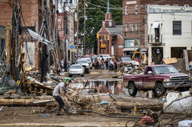 Workers, community members, and business owners clean up debris in the aftermath of Hurricane Helene in Marshall, N.C., on Sept. 30, 2024.