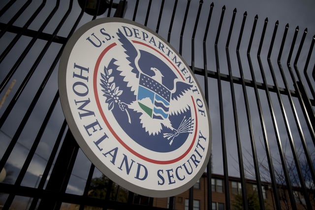 The U.S. Department of Homeland Security (DHS) seal hangs on a fence at the agency's headquarters in Washington, D.C., U.S., on Thursday, Dec. 11, 2014. The U.S. House is set to pass a $1.1 trillion spending bill that includes a banking provision opposed by many Democrats as a giveaway to large institutions. Current funding for the government ends today, and the measure would finance most of the government through September 2015. The DHS, responsible for immigration policy, would be financed only through Feb. 27. Photographer: Andrew Harrer/Bloomberg via Getty Images