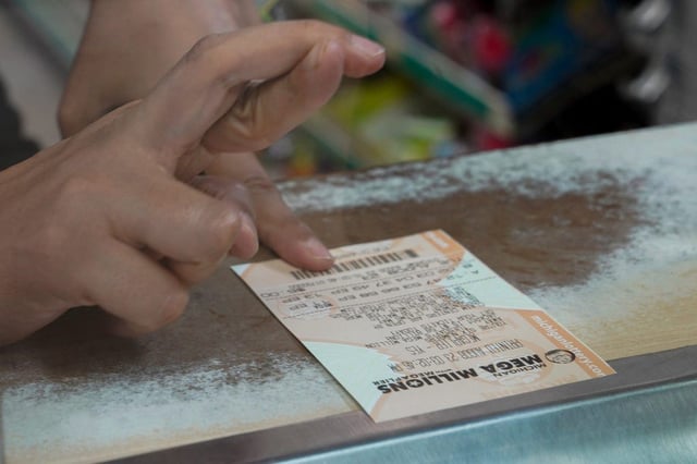 A woman crosses her fingers after purchasing a Mega Millions lottery ticket.