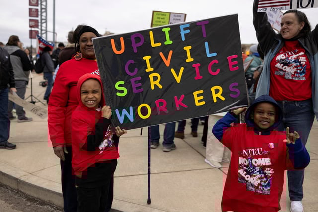 Denise Davis, a retired federal employee and NTEU union member, looks on as her great grandsons' Deondre and Montrell Griffin hold a sign during a rally across the street from the Internal Revenue Service (IRS) headquarters, in support of the civil service in the wake of mass firings, and organized by the National Treasury Employees Union (NTEU) in Kansas City, Missouri, U.S. March 15, 2025.  REUTERS/Chase Castor/File Photo