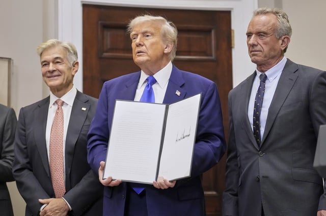 President Donald Trump, with Dr. Mehmet Oz, Administrator of the Centers for Medicare & Medicaid Services, left, and Health and Human Services Secretary Robert F. Kennedy Jr., right, holds an executive order related to drug prices, in the Roosevelt Room of the White House in Washington, Monday, May 12, 2025, in Washington. (AP Photo/Mark Schiefelbein)