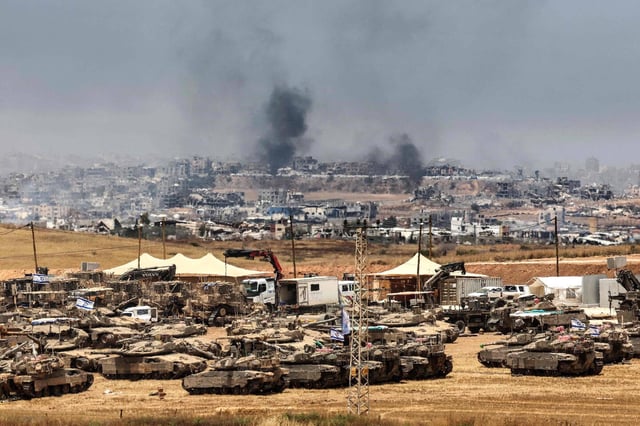 Des chars et des bulldozers israéliens déployés tandis que de la fumée s'élève au-dessus des bâtiments détruits à Gaza lors d'un bombardement israélien, le 17 mai 2025.