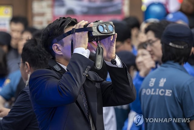 A security personnel member operates specialized binoculars during a rally for Democratic Party presidential candidate Lee Jae-myung in Geoje, about 330 kilometers southeast of Seoul, on May 14, 2025. (Yonhap)