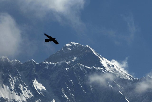 FILE - A bird flies in the backdrop of Mount Everest, as seen from Namche Bajar, Solukhumbu district, Nepal on May 27, 2019. (AP Photo/Niranjan Shrestha, File)